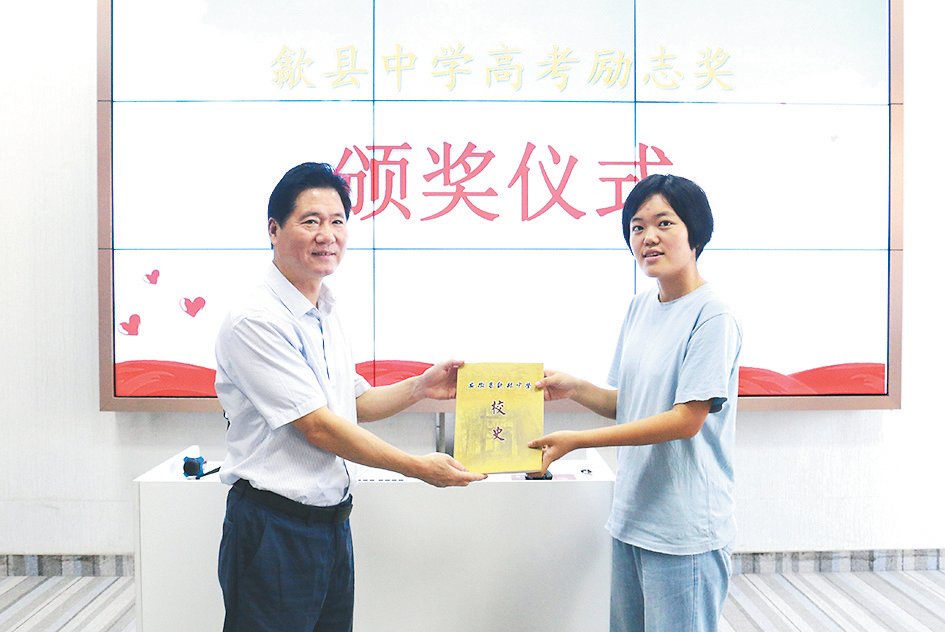 汪小龙校长给该校市文科第一名徐一涛同学赠送校史书